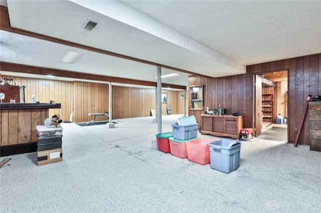 basement with carpet, bar area, and wood walls