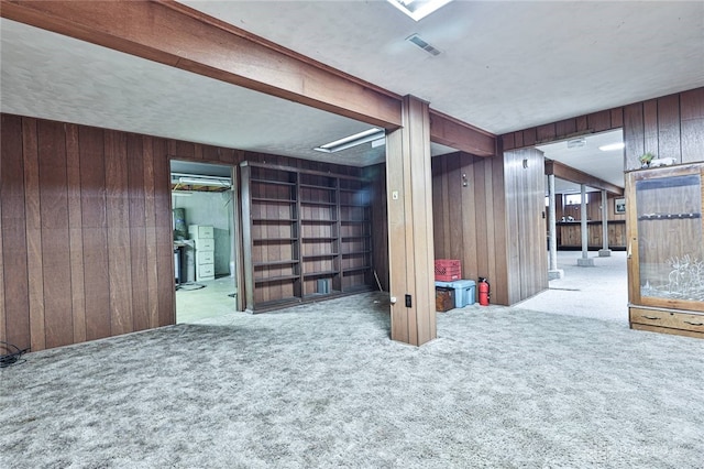 basement featuring light carpet and wooden walls