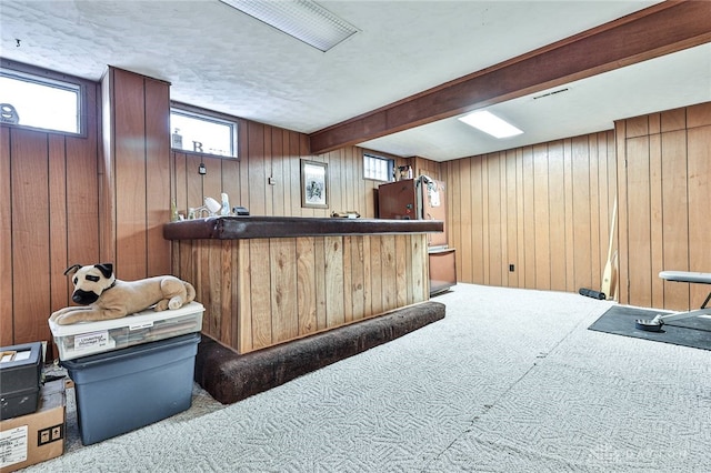 bar with refrigerator, beam ceiling, wood walls, and carpet flooring