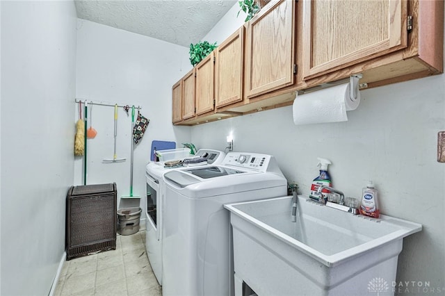 laundry room featuring cabinets, sink, washing machine and clothes dryer, and a textured ceiling