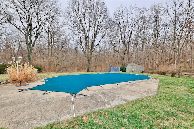 view of swimming pool with a shed and a lawn