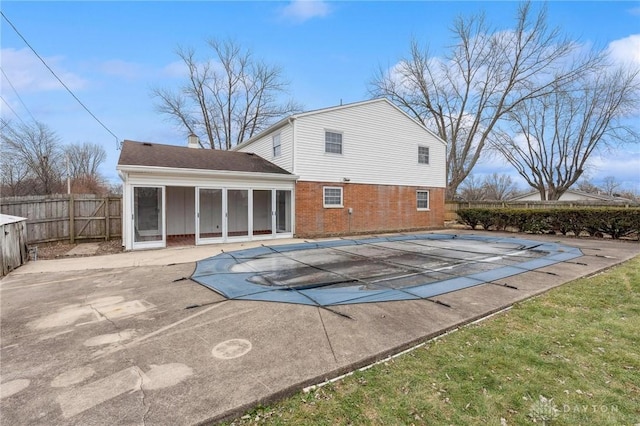 back of house with a sunroom, a covered pool, and a patio area