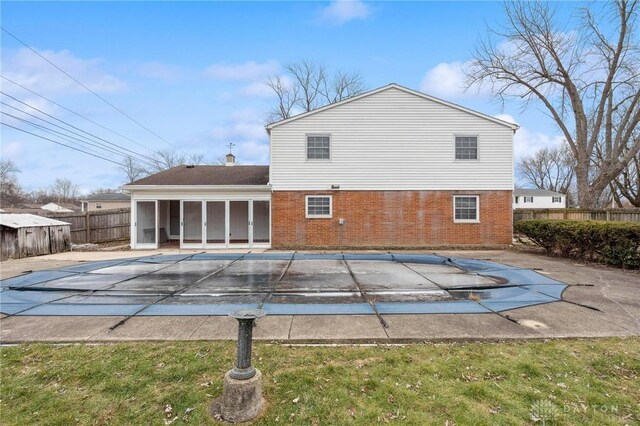 rear view of property with a covered pool, a patio area, a sunroom, and a lawn