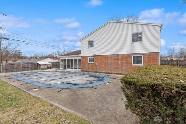 back of house with a sunroom, a patio, and a covered pool