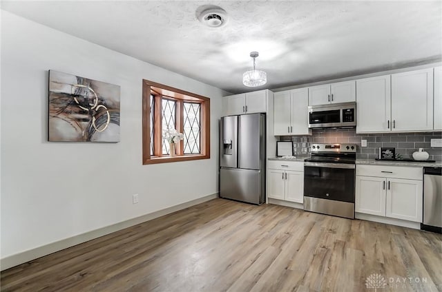 kitchen with white cabinetry, tasteful backsplash, light hardwood / wood-style flooring, pendant lighting, and stainless steel appliances