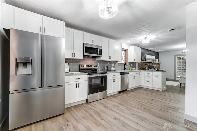 kitchen featuring tasteful backsplash, stainless steel appliances, light hardwood / wood-style floors, and white cabinets