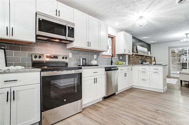 kitchen with white cabinetry, light stone counters, tasteful backsplash, appliances with stainless steel finishes, and light hardwood / wood-style floors