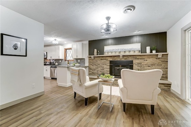 living room featuring a textured ceiling, a fireplace, and light hardwood / wood-style floors