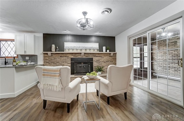 living area with plenty of natural light, a brick fireplace, and light wood-type flooring