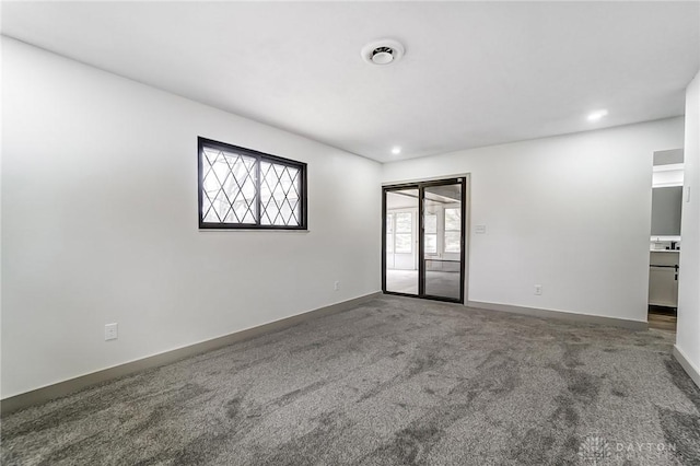 spare room featuring plenty of natural light and dark colored carpet