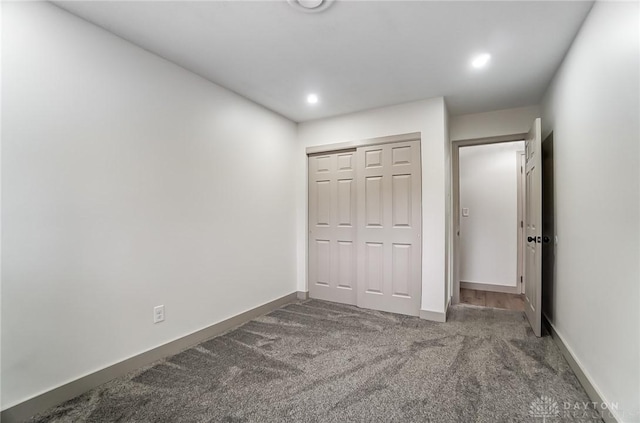 unfurnished bedroom with dark carpet and a closet