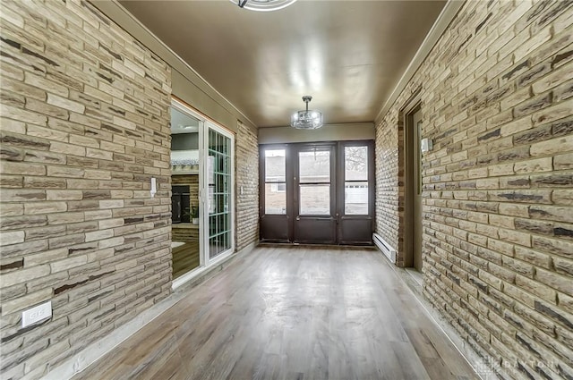 unfurnished sunroom with an inviting chandelier, a baseboard heating unit, and a fireplace