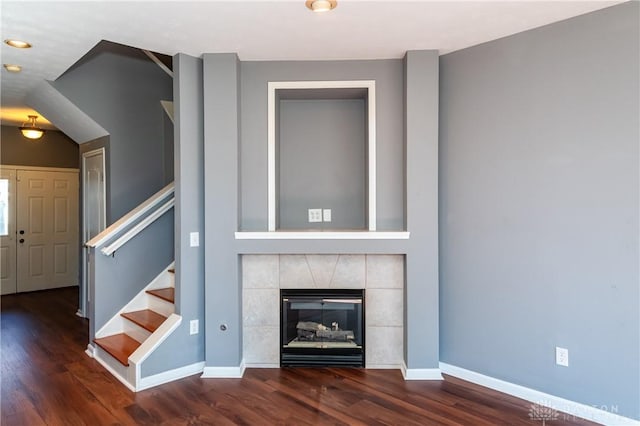 unfurnished living room with a tiled fireplace and dark hardwood / wood-style floors