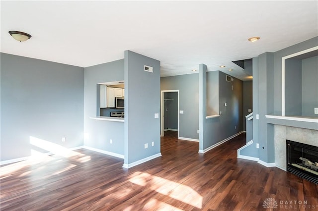 unfurnished living room featuring dark wood-type flooring and a tile fireplace