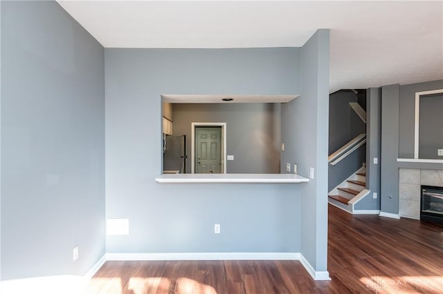 unfurnished room featuring dark wood-type flooring and a tile fireplace