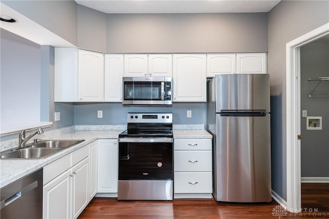 kitchen with appliances with stainless steel finishes, dark hardwood / wood-style floors, sink, white cabinets, and light stone countertops