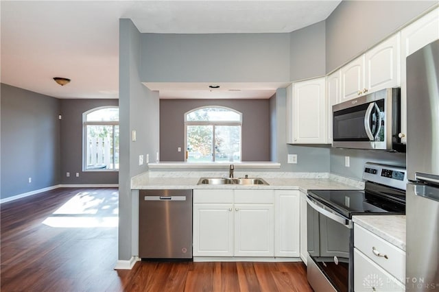 kitchen with appliances with stainless steel finishes, sink, white cabinets, and dark hardwood / wood-style flooring