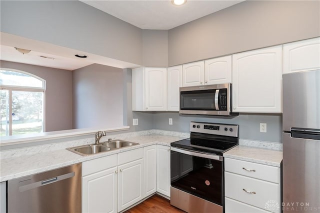 kitchen with white cabinetry, sink, stainless steel appliances, light stone countertops, and light hardwood / wood-style flooring