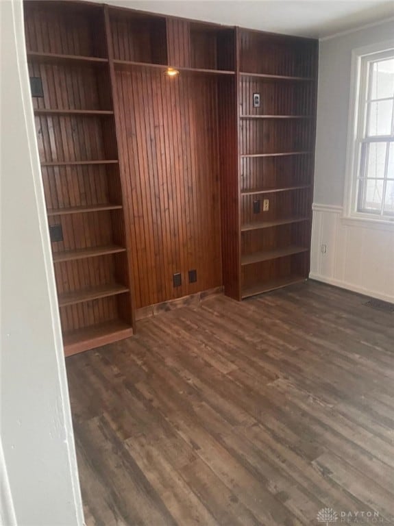 spare room featuring built in shelves and dark hardwood / wood-style floors