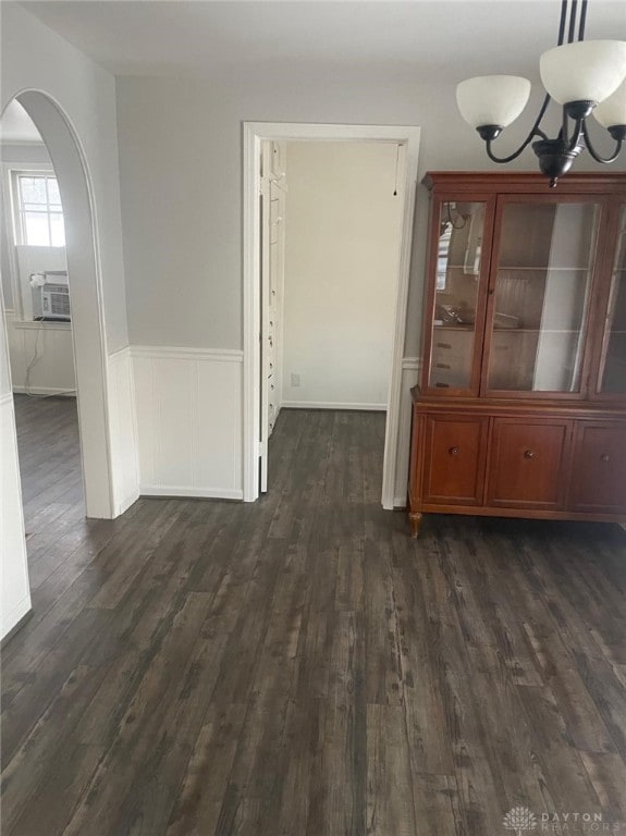 unfurnished dining area featuring dark hardwood / wood-style flooring, cooling unit, and an inviting chandelier