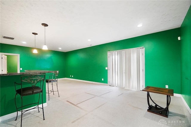 kitchen with pendant lighting, a breakfast bar, light carpet, and a textured ceiling