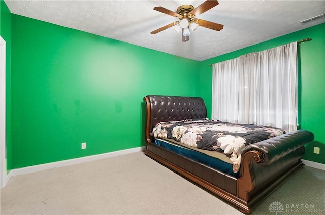 carpeted bedroom featuring ceiling fan and a textured ceiling