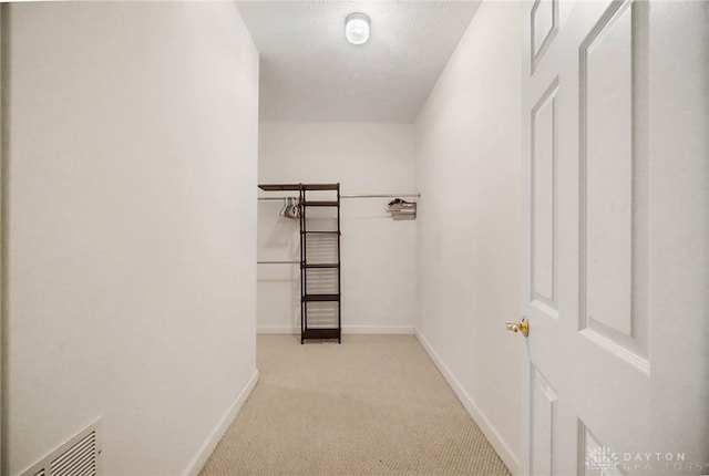 walk in closet featuring light colored carpet