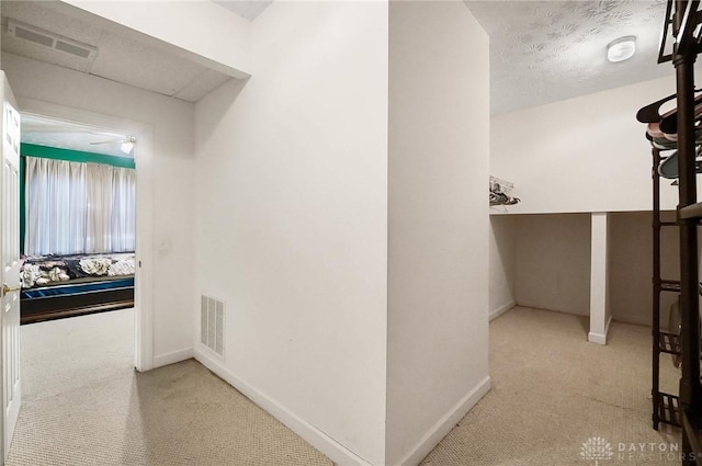 corridor with light carpet and a textured ceiling