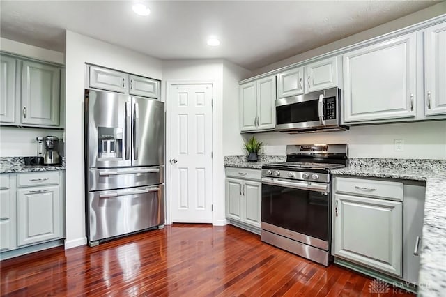 kitchen with light stone countertops, appliances with stainless steel finishes, and dark hardwood / wood-style floors