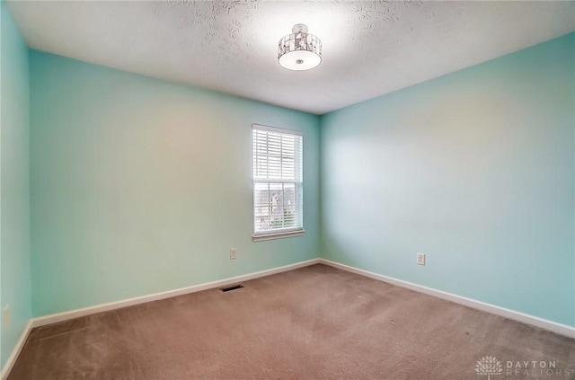 spare room featuring a textured ceiling and carpet