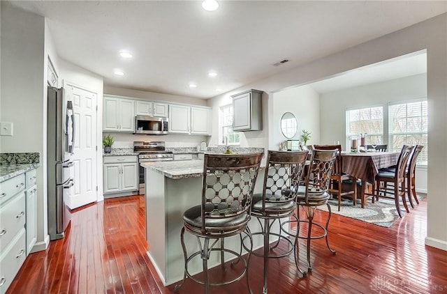 kitchen featuring light stone counters, gray cabinets, stainless steel appliances, and dark hardwood / wood-style floors