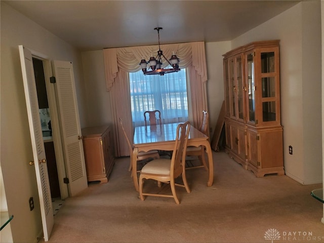 dining room with light carpet and a notable chandelier