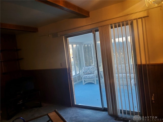 doorway featuring beam ceiling and carpet