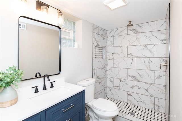 bathroom with vanity, toilet, and a tile shower