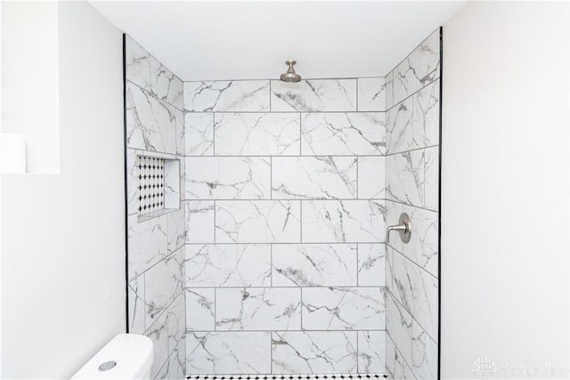 bathroom featuring a tile shower and toilet