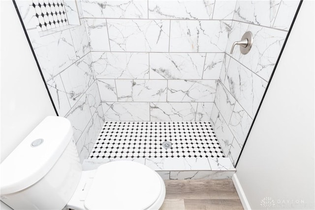 bathroom featuring a tile shower and toilet