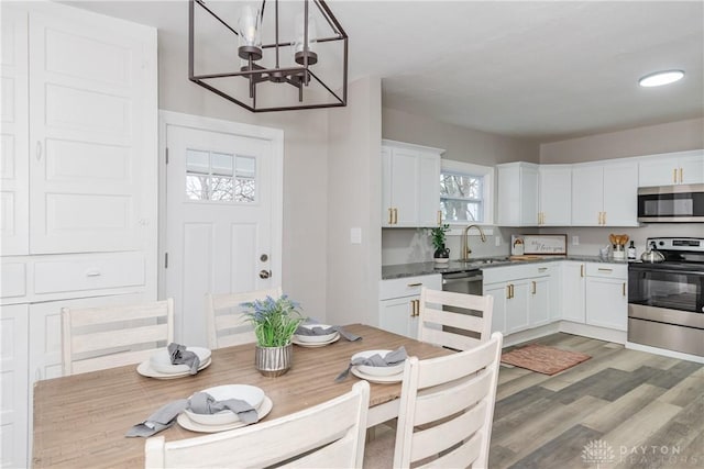 kitchen with white cabinetry, sink, decorative light fixtures, and appliances with stainless steel finishes