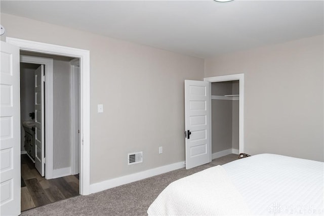 bedroom with dark colored carpet and a closet