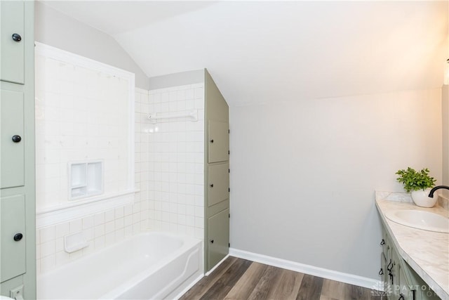 bathroom with tiled shower / bath combo, wood-type flooring, lofted ceiling, and vanity