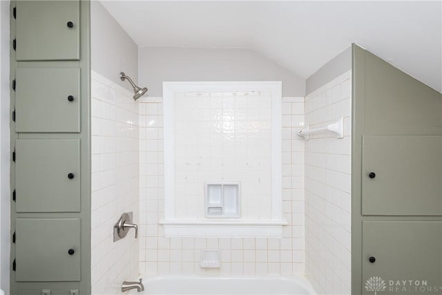 bathroom with tiled shower / bath combo and lofted ceiling