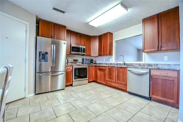 kitchen with stainless steel appliances, sink, a textured ceiling, and light tile patterned floors