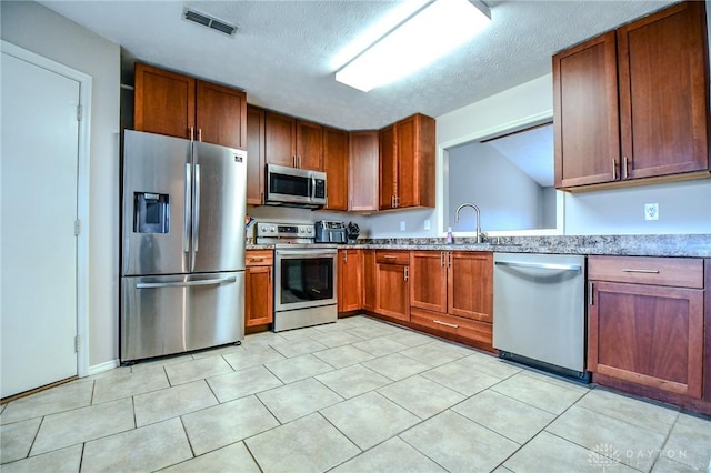 kitchen featuring stainless steel appliances, sink, a textured ceiling, and light tile patterned floors