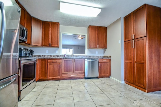 kitchen with light tile patterned flooring, sink, a textured ceiling, ceiling fan, and stainless steel appliances