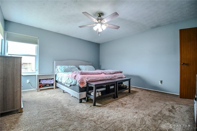 bedroom with ceiling fan, carpet floors, and a textured ceiling