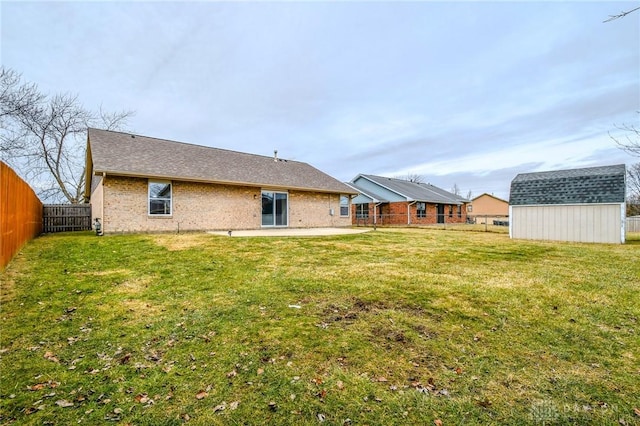 back of house with a shed, a yard, and a patio area