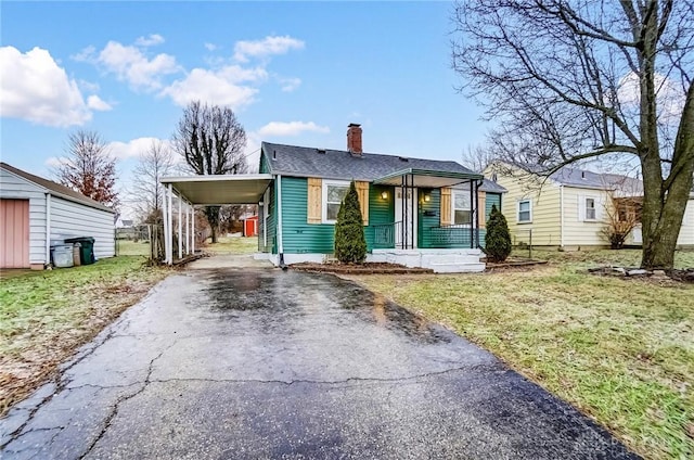 bungalow-style house with a carport, covered porch, and a front lawn