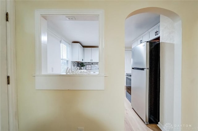 kitchen featuring stainless steel refrigerator, white cabinetry, tasteful backsplash, and stove