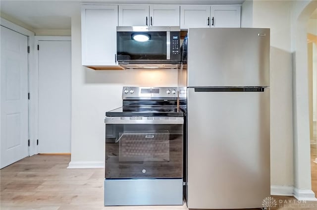 kitchen with stainless steel appliances, white cabinets, and light hardwood / wood-style floors