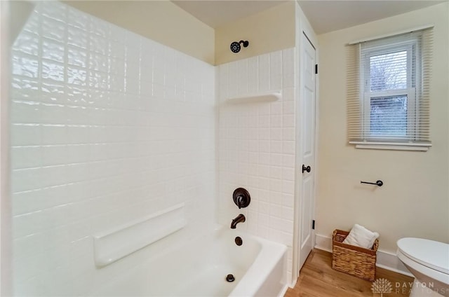 bathroom with tiled shower / bath combo, hardwood / wood-style floors, and toilet