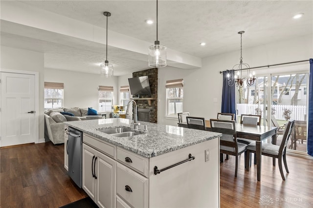 kitchen featuring pendant lighting, dishwasher, white cabinetry, sink, and a center island with sink